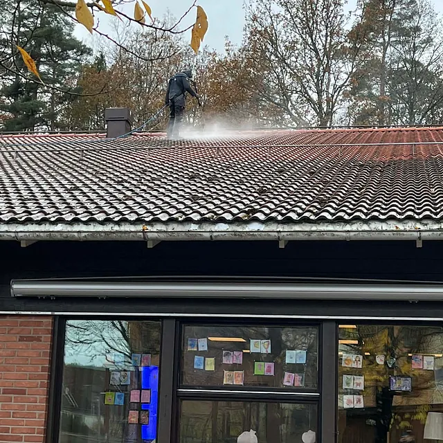 man står på taket och tvättar taket