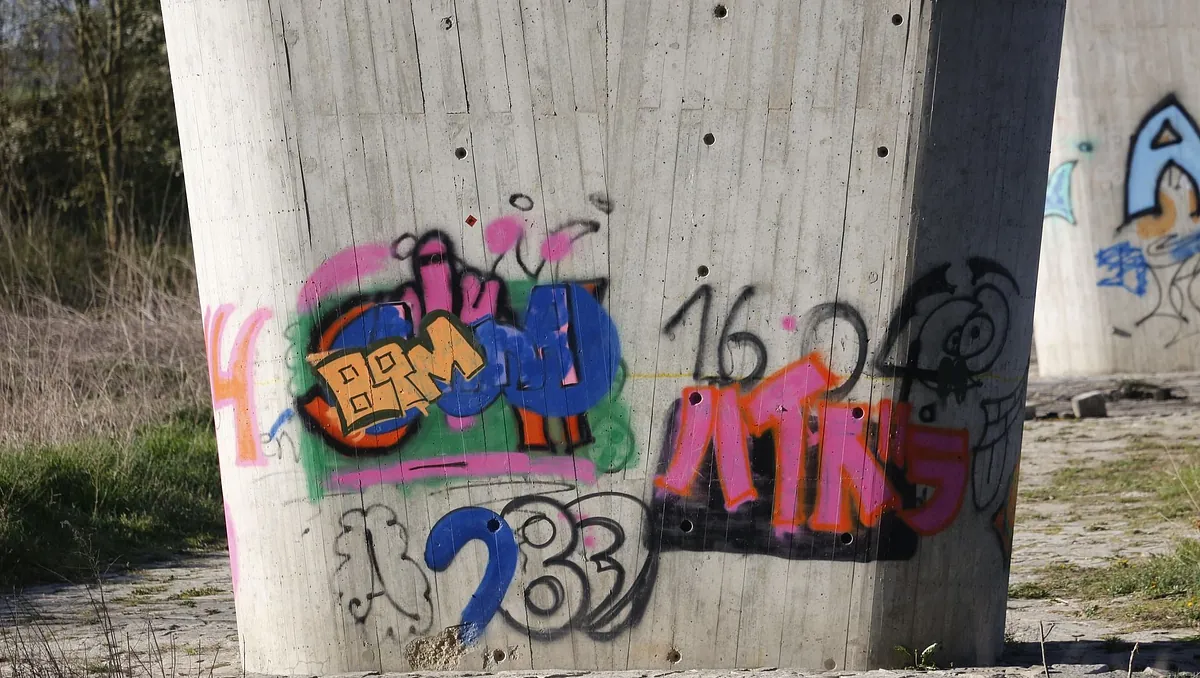 Klotter på en betongpelare som förbereds för klottersanering