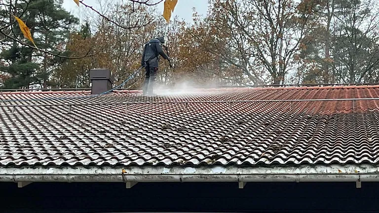 Tvättare står och tvättar husets tegeltak